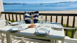 Une table dressée pour deux personnes, avec vue sur la mer et des bateaux en arrière-plan.