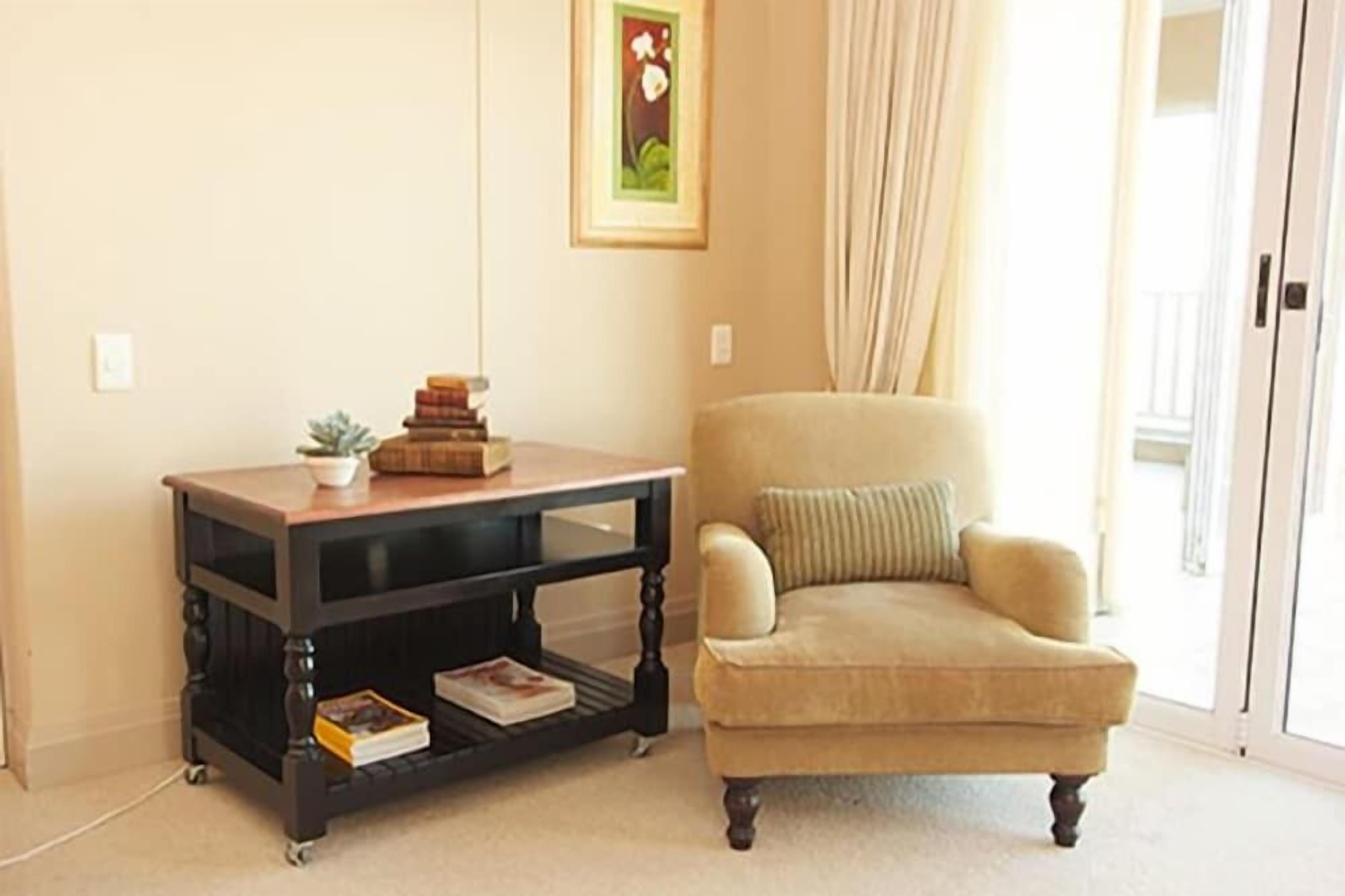 Un soggiorno con una poltrona beige, un tavolino in legno e un quadro incorniciato appeso al muro.