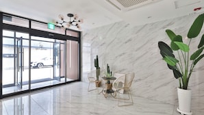A hotel lobby with a marble floor, a glass door entrance, a cactus centerpiece, and a large potted plant. - Gyeongju hotel namu (Gyeongju)