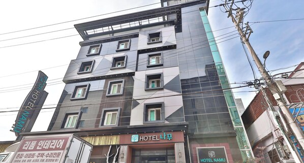 Et hotel med flere etager og en moderne facade, der viser en tydelig logo og skilte, som angiver, at det er Hotel Namu.