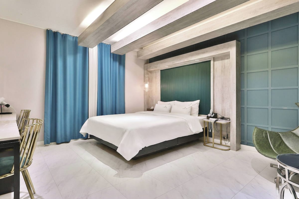 A modern hotel room with a large bed, a desk, and a chair.