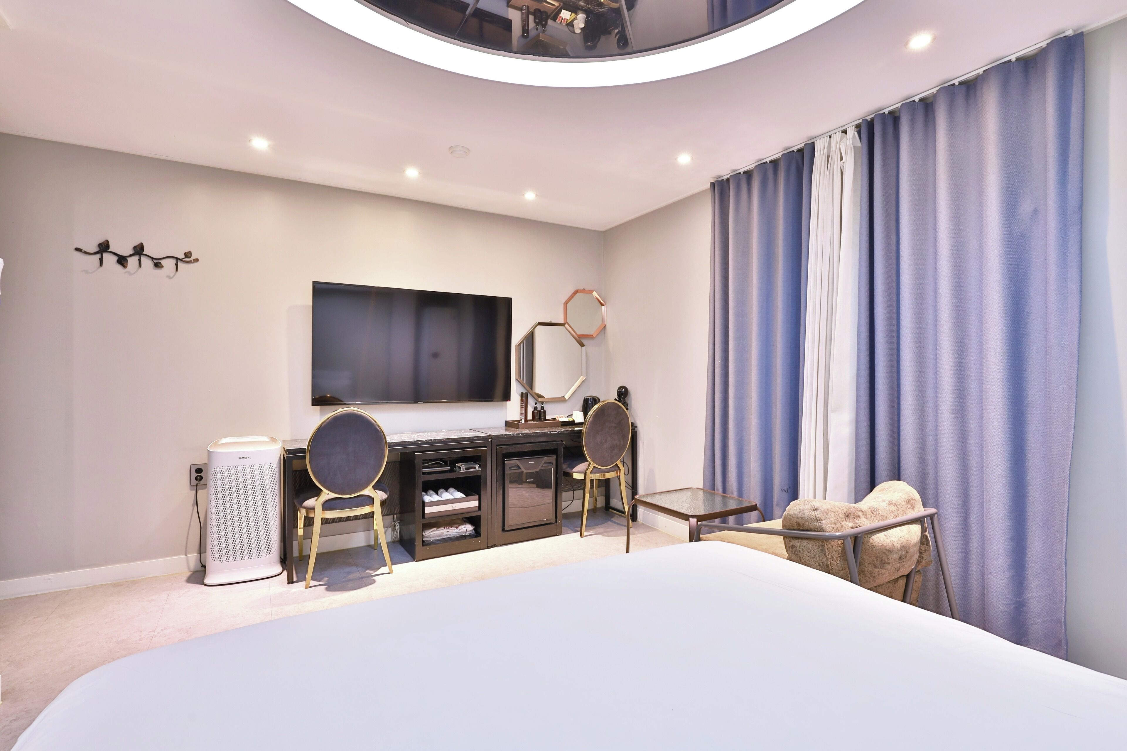 Un dormitorio moderno con una cama grande, un escritorio con silla, un televisor y un armario.