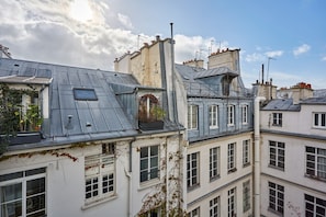 A row of European-style buildings with multiple stories, featuring a mix of flat and sloped roofs, and visible chimneys. - Chic Duplex Loft in the Heart of Paris Montorgueil (Paris)