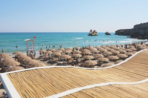 Ein Strand mit vielen Sonnenschirmen und einem Rettungsturm.