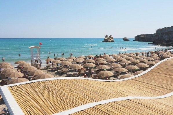 A beach with numerous umbrellas and a lifeguard tower. - Futura Club Barone di Mare (Melendugno)