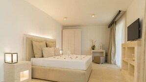 A modern hotel room with a large bed, bedside tables, a flat-screen TV, and a small side table with a lamp. - Futura Club Barone di Mare (Melendugno)