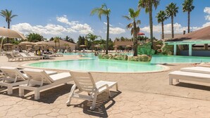 A pool area with lounge chairs, palm trees, and a covered seating area. - Futura Club Barone di Mare (Melendugno)