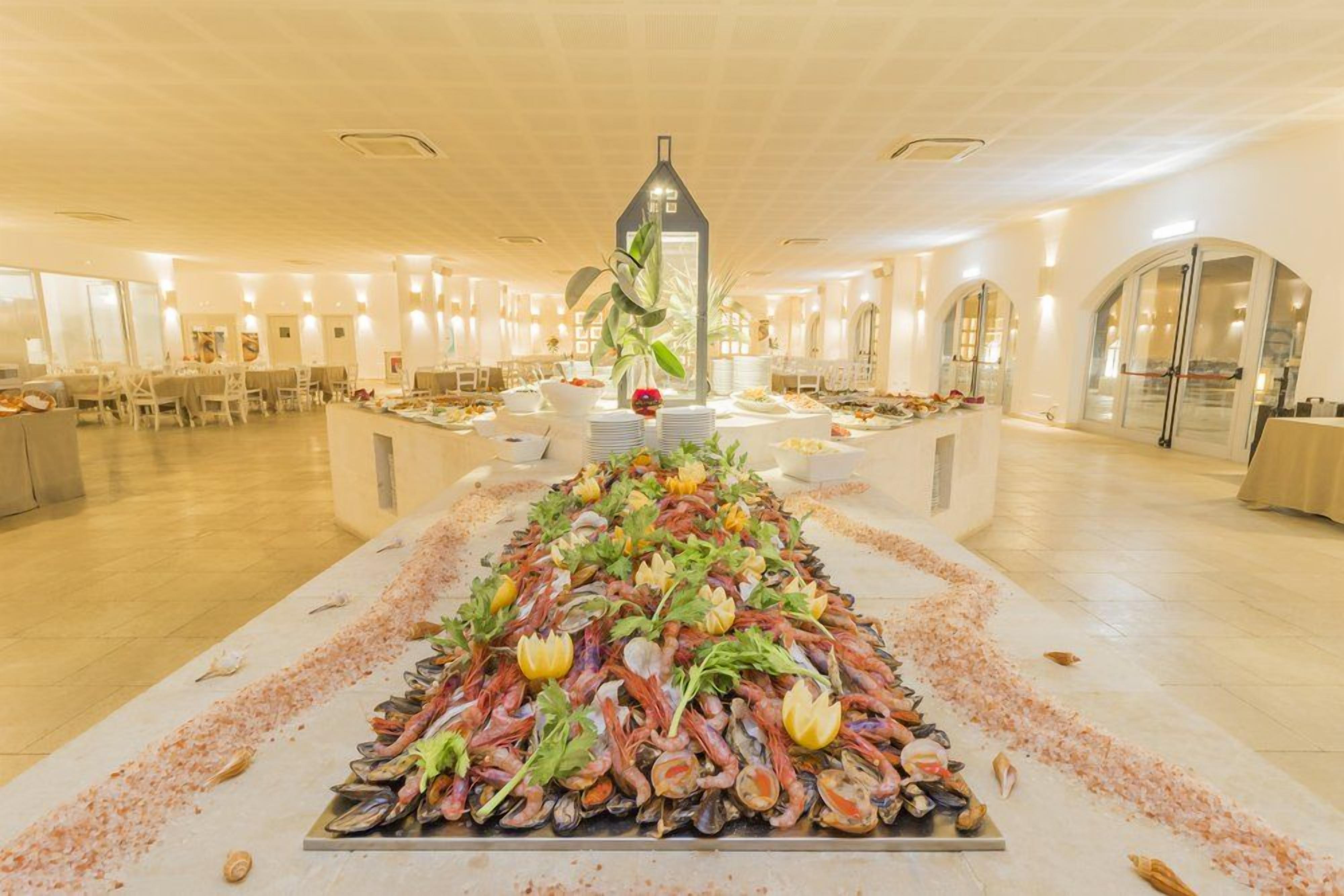 A spacious hotel dining area with a central seafood display, multiple tables, and a modern architectural design.