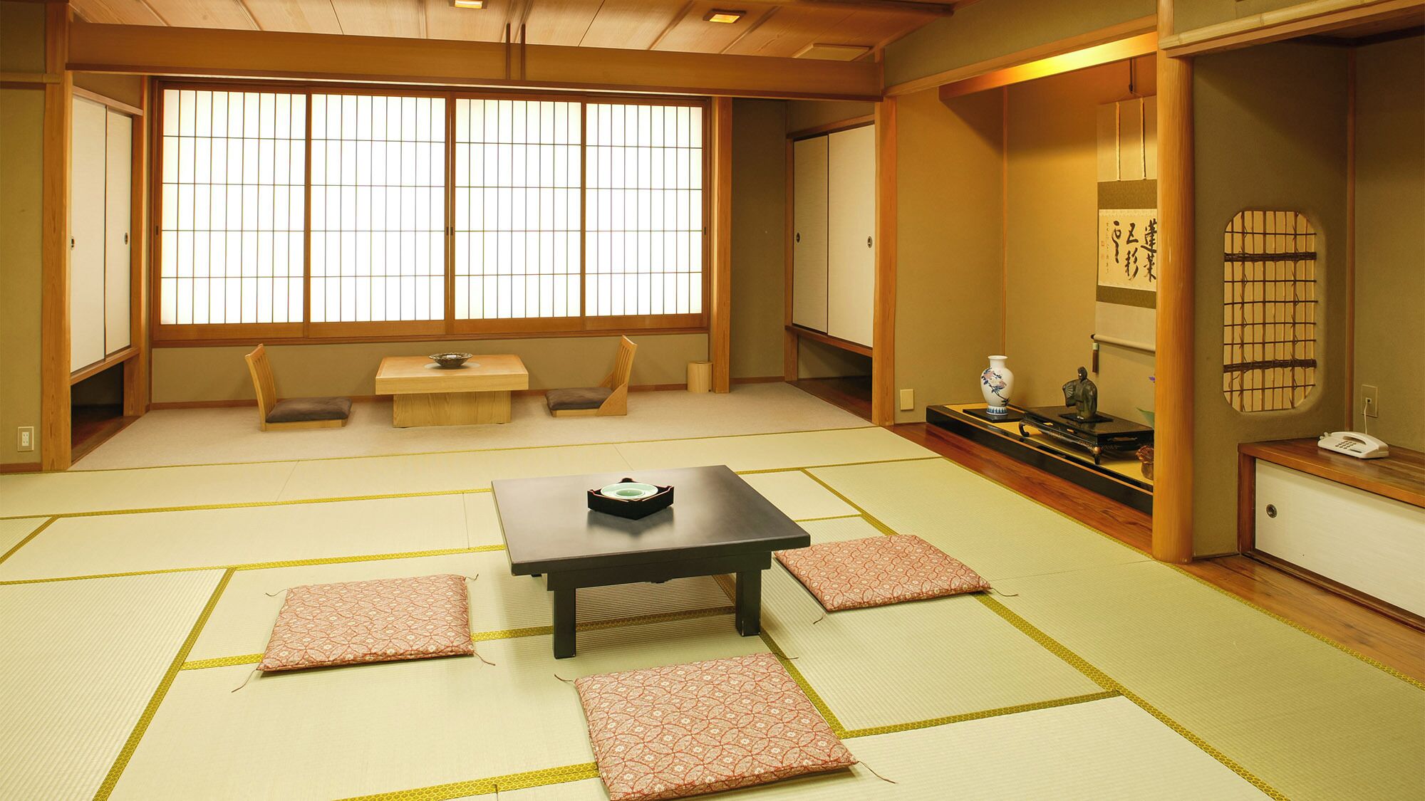A traditional Japanese room with tatami flooring, a low table with cushions, and sliding doors.