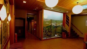 Een klassiek interieur met houten balken, een kamer met tatami matten, een shoji schuifwand en een trap.