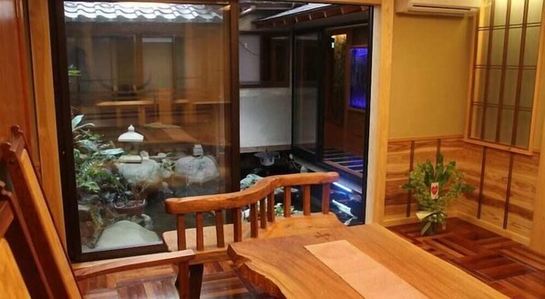 A wooden interior with a wooden staircase, a dining table, and a view through a glass door to a kitchen area. - Kinosaki Onsen Shinonomesou (Toyooka)