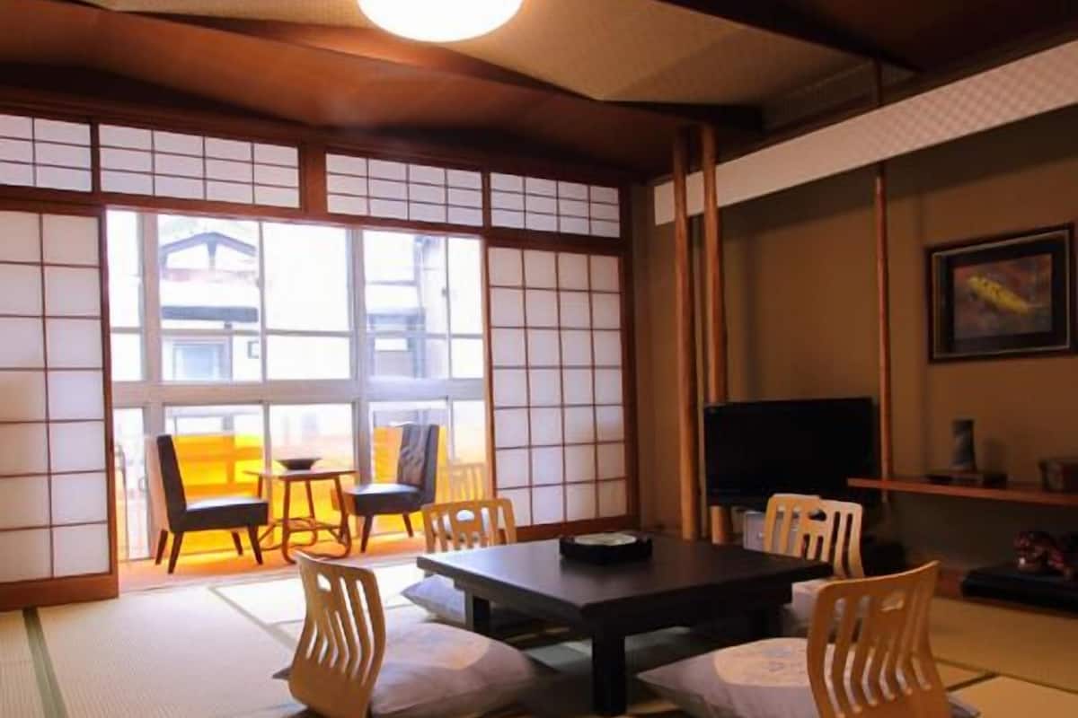 Una habitación japonesa tradicional con suelo de tatami, una mesa baja y puertas correderas.