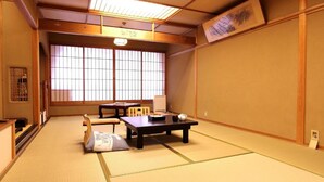 Een traditionele Japanse kamer met tatami vloerbedekking, een lage tafel en schuifdeuren.