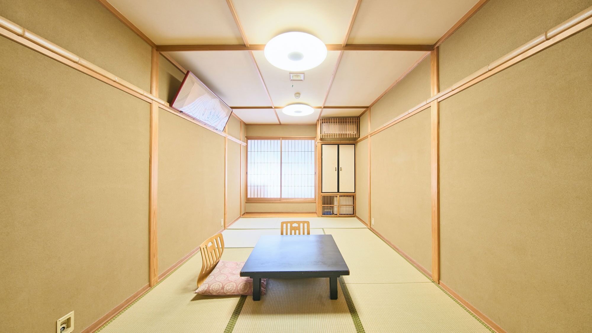 A traditional Japanese room with tatami flooring, a low table, and sliding doors.