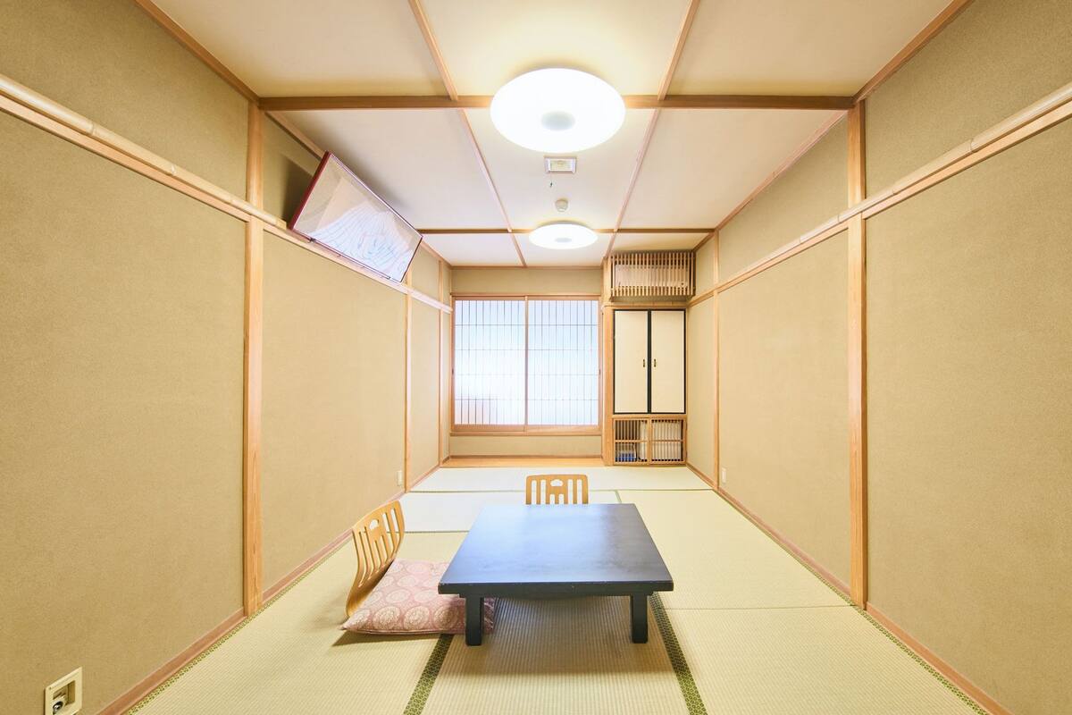 Una habitación japonesa tradicional con suelo de tatami, una mesa baja y puertas correderas.