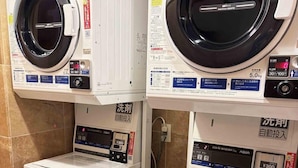 Two front views of a washing machine with a digital display, a control panel, and a coin slot for payment.