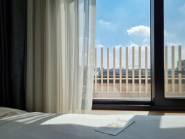Habitación de hotel con un ventanal grande, una cama y vista a la ciudad.