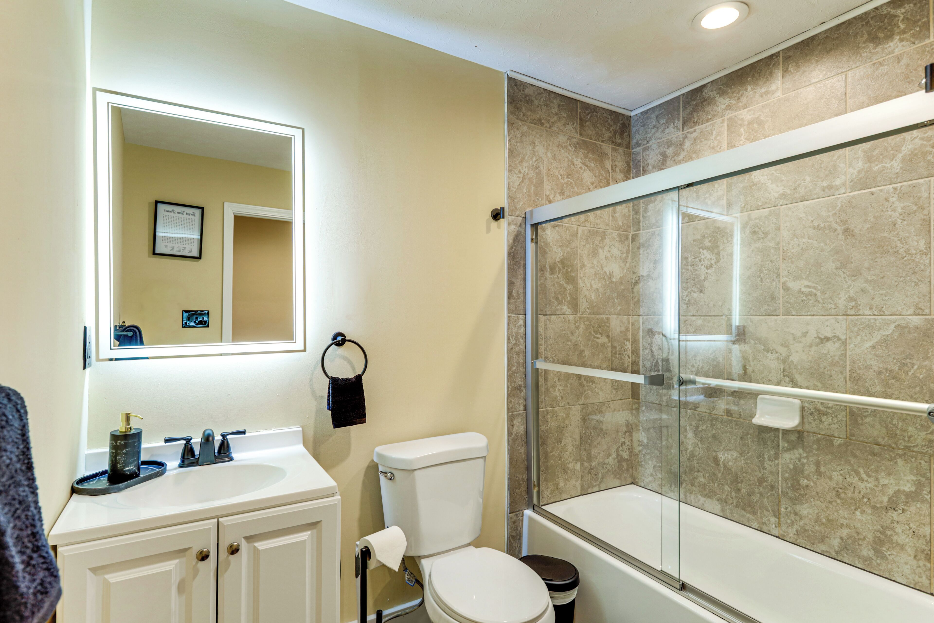 Une salle de bain avec un lavabo blanc, des toilettes et une douche fermée par des parois de verre.