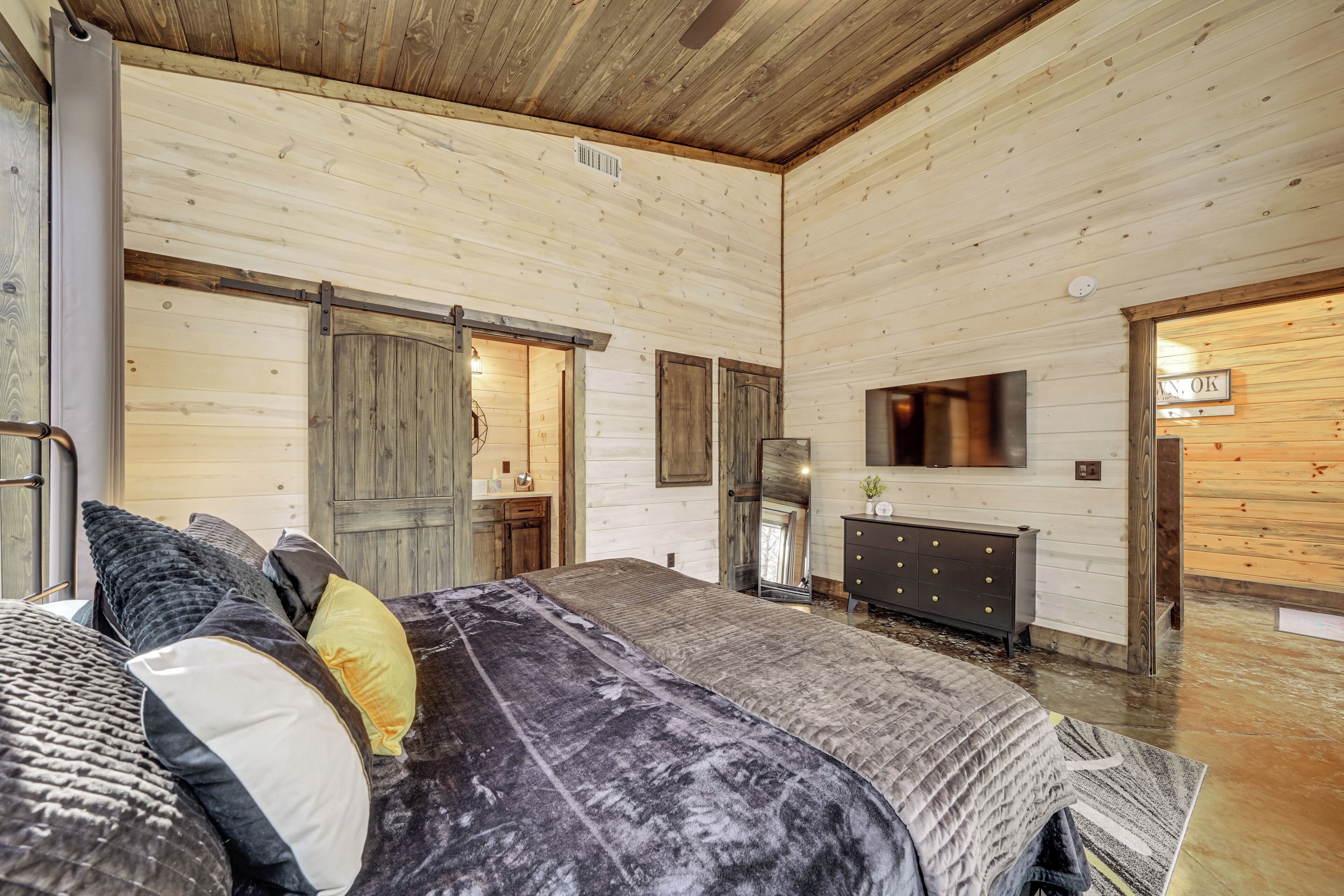 Een gezellig houten slaapkamer met een groot bed, een dressoir en een spiegel.