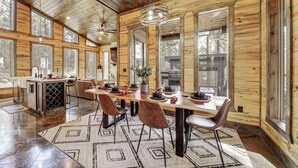 Una cabana de fusta espaiosa amb una àrea de dinar ampla, una cuina i grans finestres.