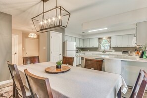 A modern kitchen with white cabinets, a central island, and a dining area with a round table and chairs. - Cottage Vibes in Shalimar! Pet-friendly Townhome (Shalimar)