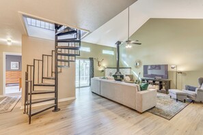 Un salon spacieux doté d’un escalier moderne, d’une cheminée, d’un grand téléviseur et d’un coin salon confortable.