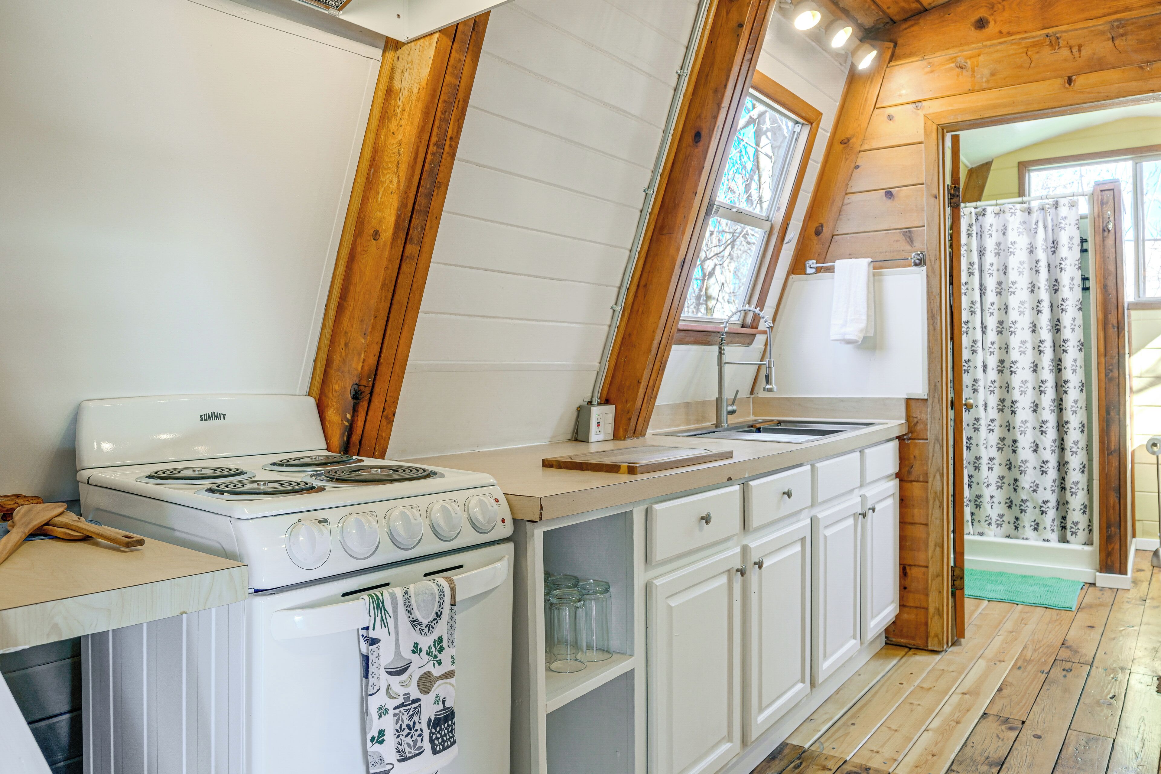 A kitchen with white cabinets, a stove, and a window.
