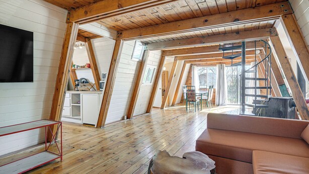 A loft-style room with a wooden floor, a red metal bench, a brown sofa, and a staircase leading to an upper level. - Hike, Bike & Atv! A-frame Rimrock Cabin w/ Views (Rimrock)