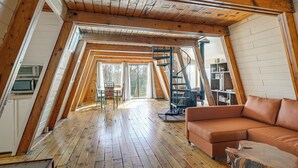 An attic bedroom with wooden beams, a loft bed, a wooden floor, a sofa, and a ladder. - Hike, Bike & Atv! A-frame Rimrock Cabin w/ Views (Rimrock)
