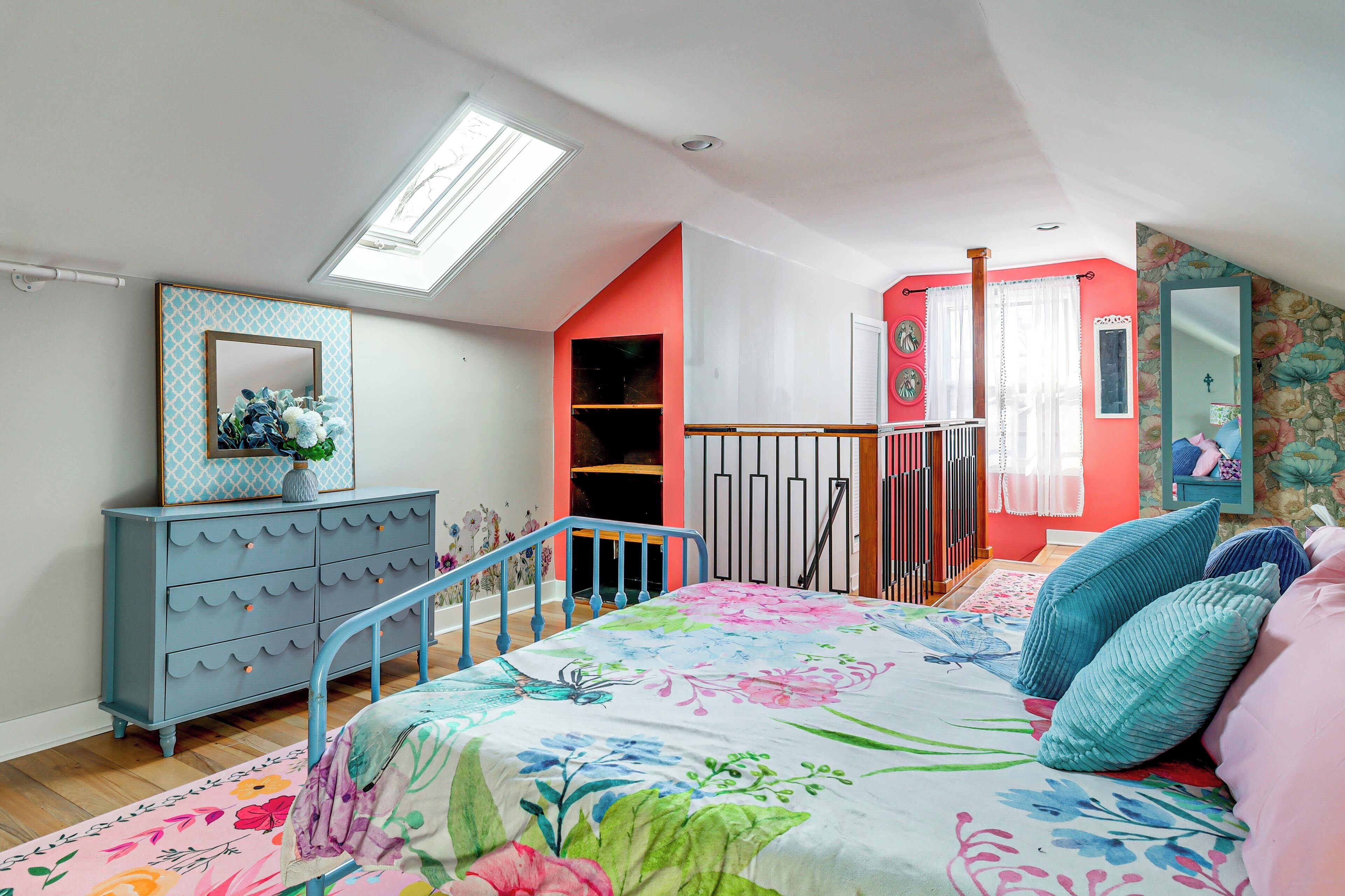 A bedroom with a bed, dresser, and skylight.