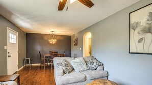 Ein Wohnzimmer mit grauem Sofa, gemusterten Kissen, einem Holztisch und einer Kristallleuchter.