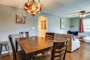 A dining area with a wooden table and chairs, a stained glass light fixture, and a television in the background. - Explore the Front Range! Lakewood Home w/ Yard (Lakewood)