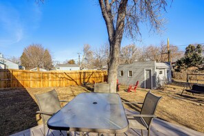 A backyard with a metal table and chairs, a wooden deck, a tree, and a small shed. - Explore the Front Range! Lakewood Home w/ Yard (Lakewood)