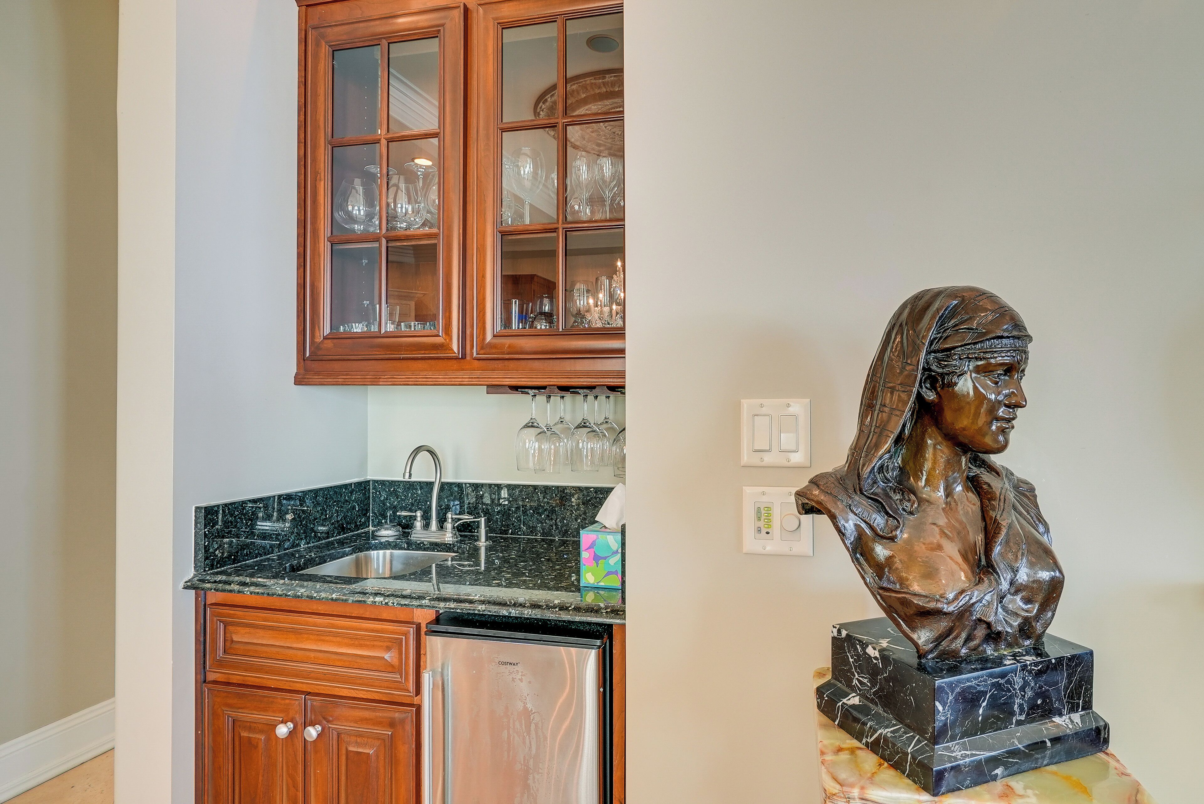 A kitchen with wooden cabinets, a stainless steel dishwasher, and a marble countertop.