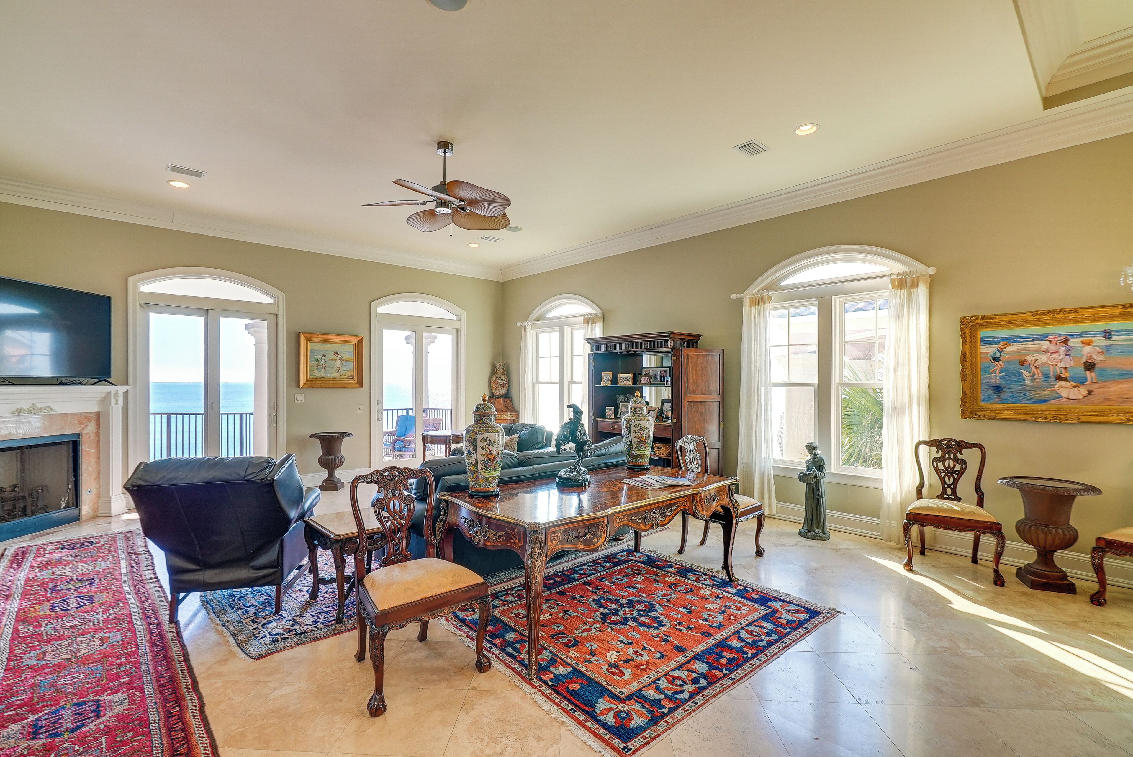 A spacious living room with a fireplace, a large wooden coffee table, and a red and blue patterned rug.