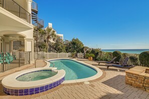 Une piscine avec un jacuzzi, des chaises longues et une vue sur l’océan.