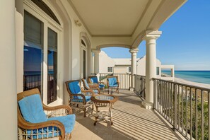 Varanda com móveis de vime e vista para o mar.