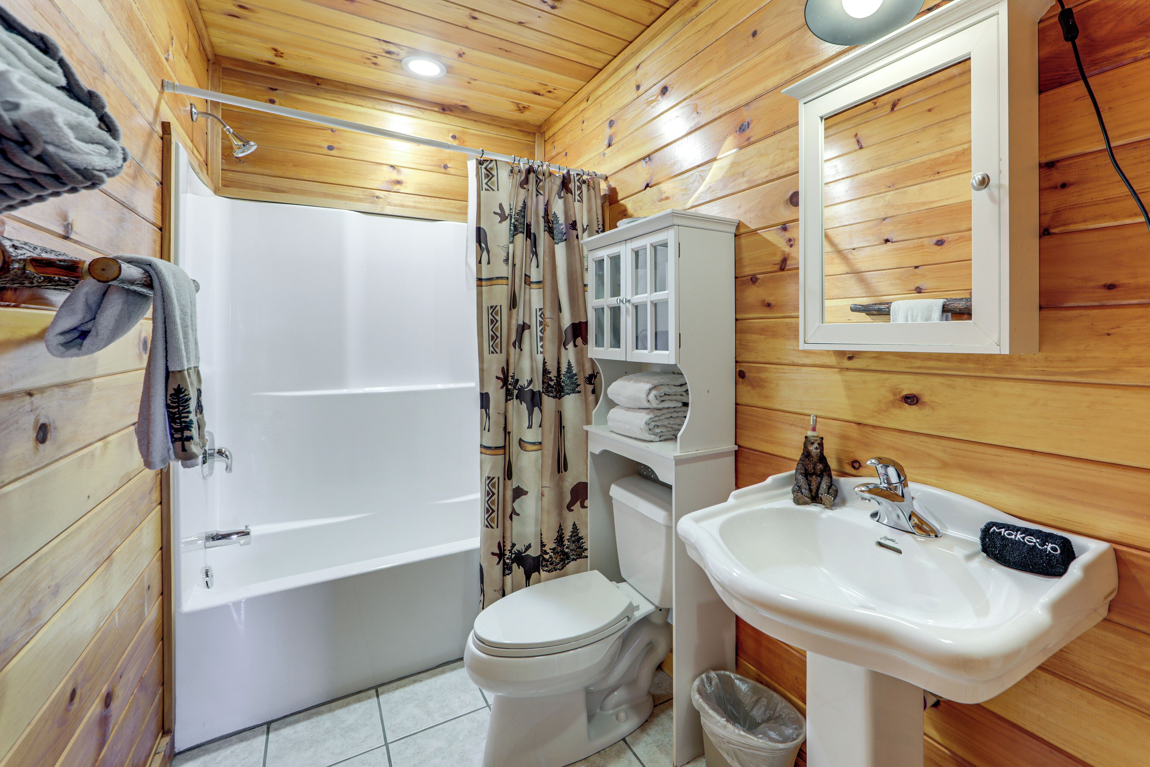Et badeværelse i en træhytte med badekar, toilet, vask og et spejl.