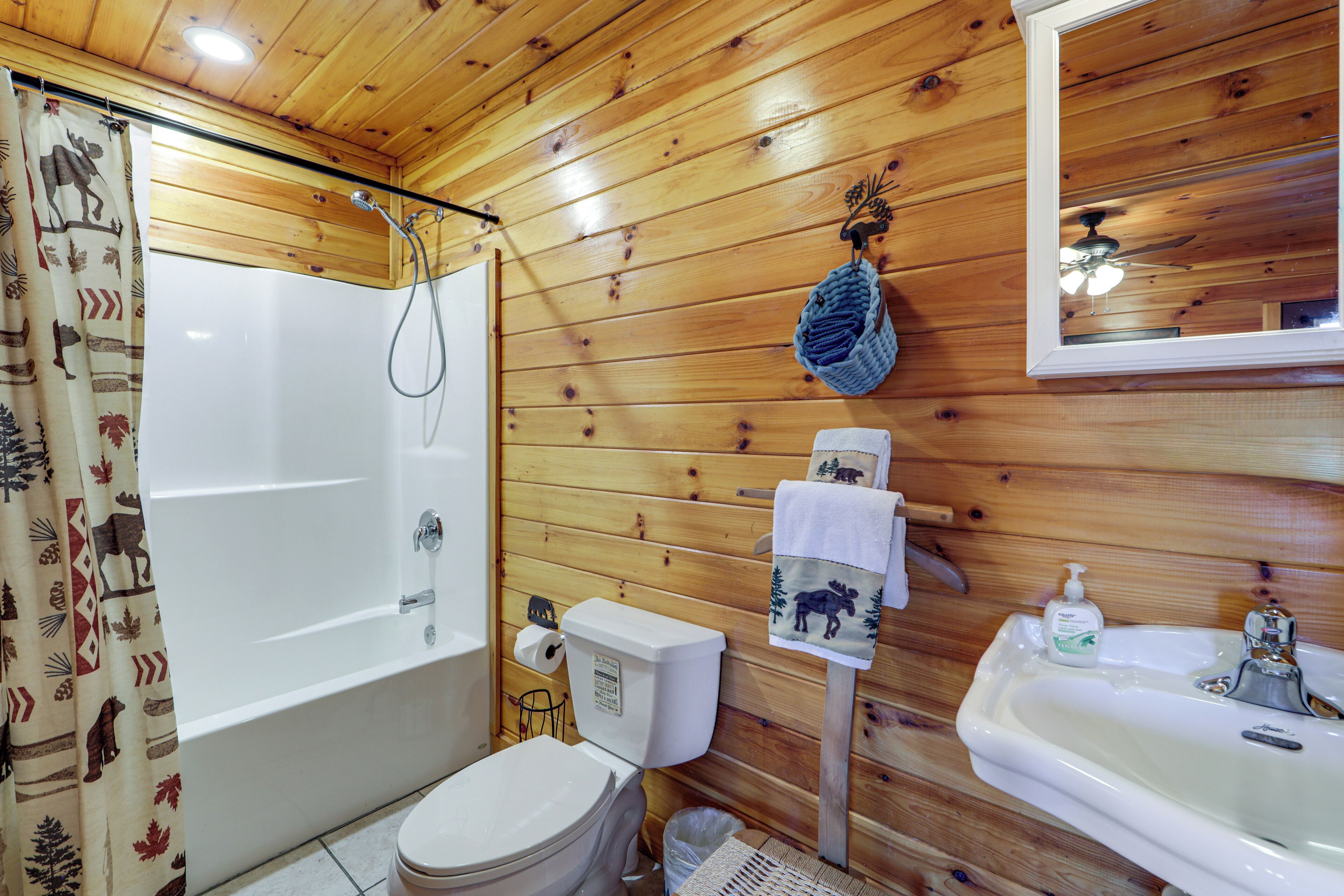Un baño con paneles de madera, una bañera, un inodoro, un lavabo y un espejo.