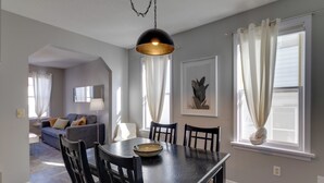 Uma sala de jantar com uma mesa, cadeiras, uma tigela e uma luminária pendente.