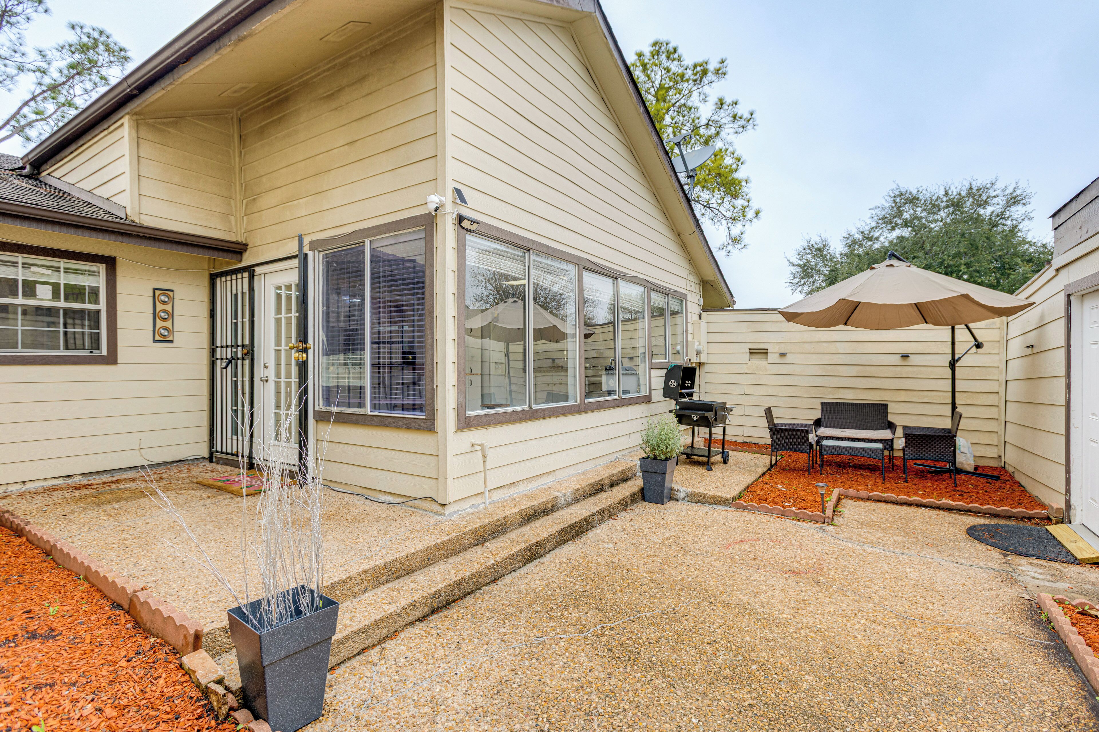 Ein Haus mit überdachter Terrasse, Grill und Gartenmöbeln.