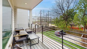 Ein Balkon mit Blick auf eine Wohngegend, darunter Häuser und ein Auto.