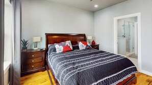 Ein Schlafzimmer mit einem hölzernen Bett, zwei Nachttischen, einem Deckenventilator und einer Duschkabine aus Glas.