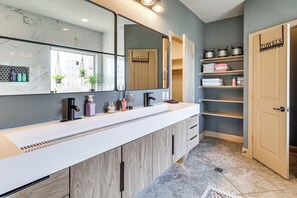 A modern bathroom with a large mirror, wooden cabinets, and a towel rack. - Pool & Hot Tub! Dog-friendly Awaysis in SE Austin (Del Valle)