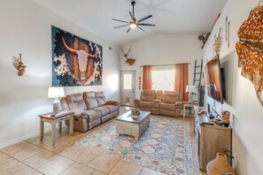 A living room with a large painting, two leather sofas, a coffee table, and a TV.