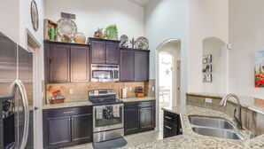 Uma cozinha moderna com armários escuros, eletrodomésticos de aço inoxidável, bancadas de granito e micro-ondas embutido.
