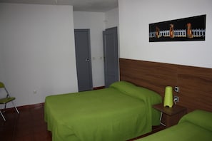 A hotel room with two beds, a wooden headboard, a framed picture on the wall, and a chair. - La Estacion Hostal (Ávila)