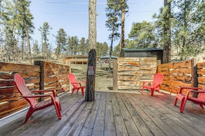 Eine Holzterrasse mit roten Adirondack-Stühlen, einem Holzzaun und einem Schild.