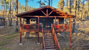 Een chalet met een houten terras en een trap naar de ingang.