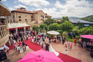 Una ceremonia de boda en un patio con alfombra roja, invitados y un edificio al fondo.